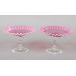 A pair of Victorian cranberry tinted vaseline glass tazza. With crimped rims and raised on