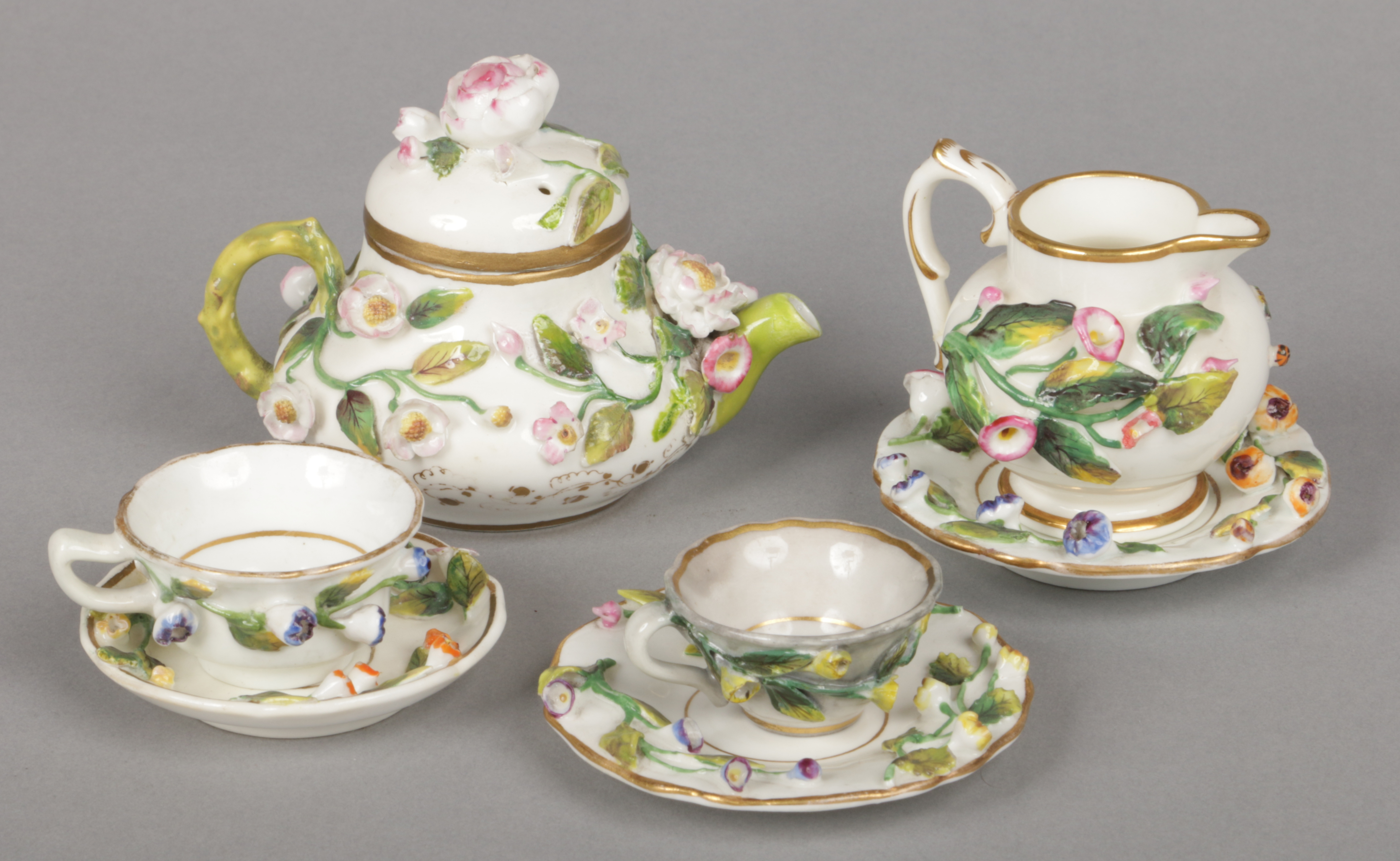An assembled Rockingham miniature part teaset. Each piece gilded and decorated with applied