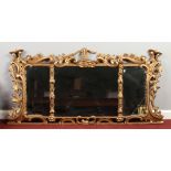 A 19th century gilt framed over mantel mirror. Decorated with S-scrolls, flowers and foliage and