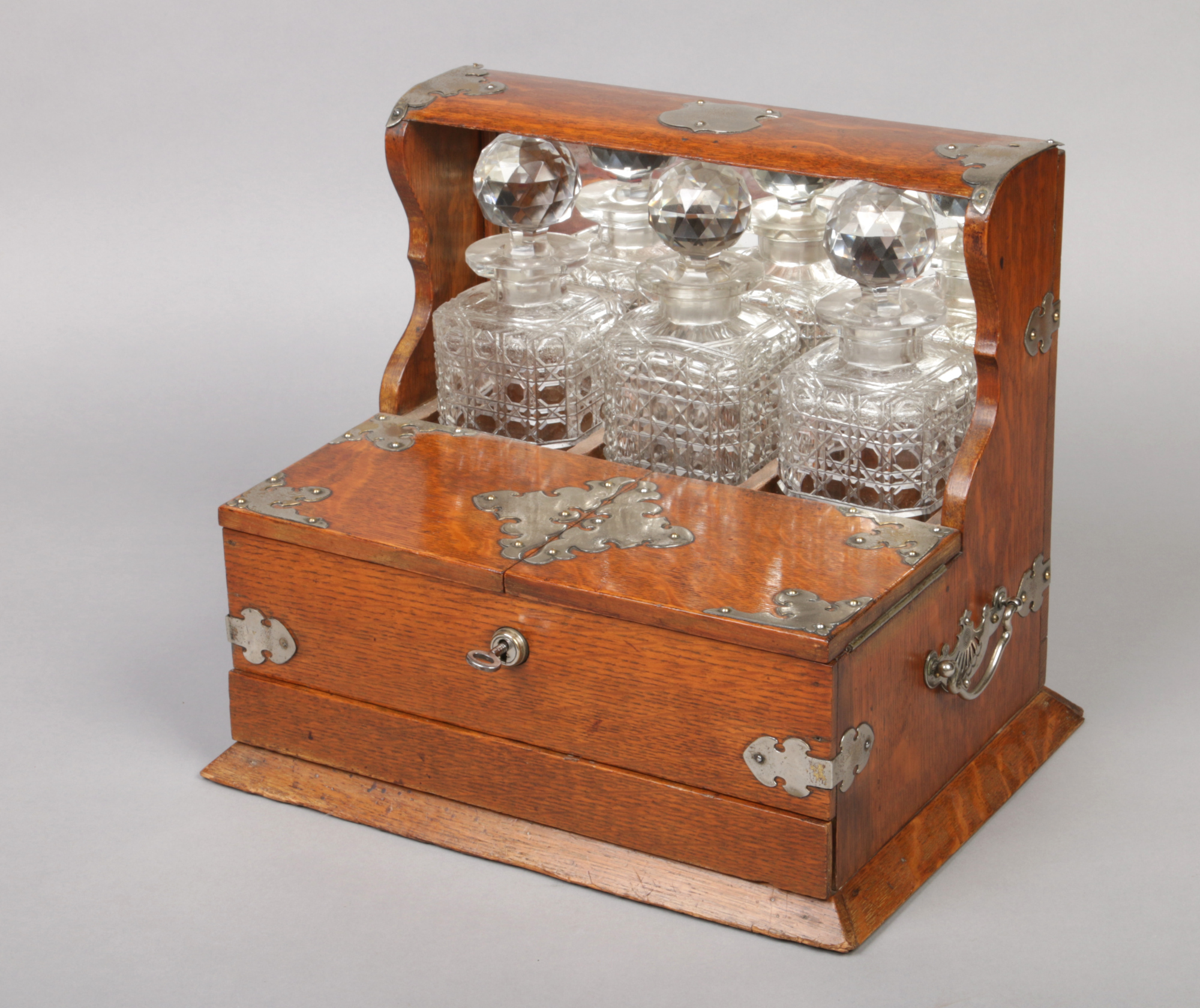 A Victorian oak three bottle tantalus with silver plated mounts. Having mirrored back and single