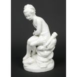 A 19th century Continental white glazed figure of a Classical huntress. Modelled seated upon a