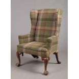 A Georgian walnut wing armchair. With tweed upholstery and raised on carved cabriole supports,