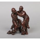 A Chinese carved hardwood figure group. Formed as a pair of jovial men and raised on a root work