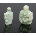 Two Chinese pale jade snuff bottles with stoppers. One carved surmounted by a mythical beast and the