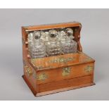 A Victorian oak brass mounted three bottle tantalus and three cut glass decanters. With mirrored