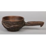 An early 20th century Continental folk art carved wooden ladle. The handle is formed as a stylized