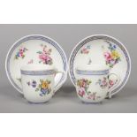 A pair of 18th century Sevres coffee cups and saucers painted with flowers under blue line and