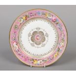 A Sevres circular cabinet plate. Painted with flowers on a pink ground, with gilt medallion centre