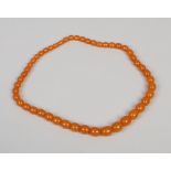 A string of ovoid graduated amber coloured beads.