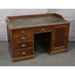 A 1930s pine office knee hole desk with inset leatherette top, W131cm x D76cm X H 86cm.