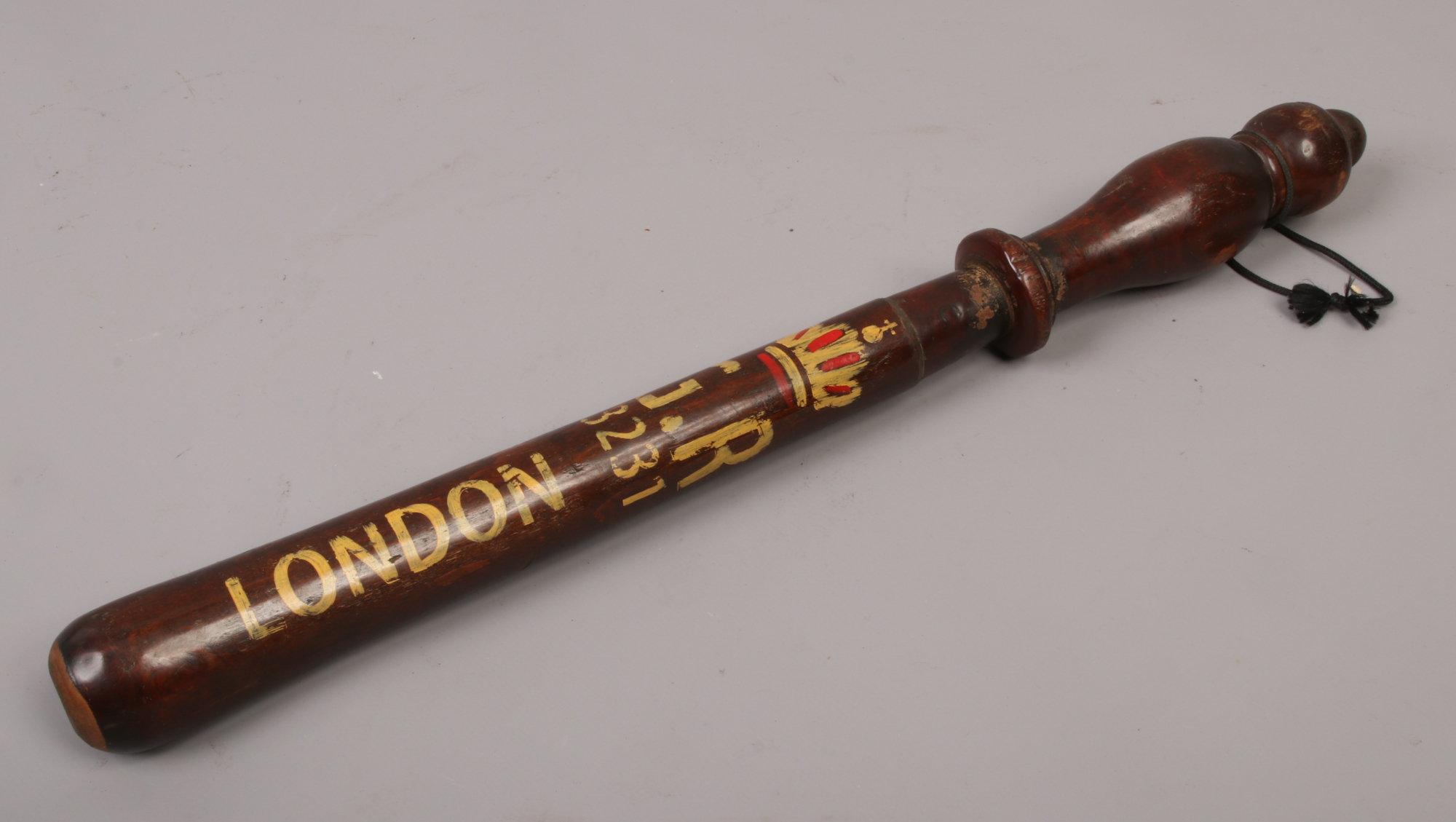 A replica of an early 20th century wooden truncheon with later stencilling.