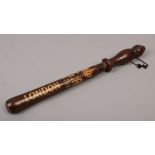 A replica of an early 20th century wooden truncheon with later stencilling.