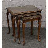 A nest of three bur walnut occasional tables, raised on slender cabriole legs.