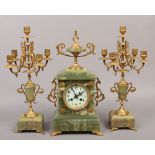 A gilt metal and onyx clock garniture including a pair of four branch candelabra.