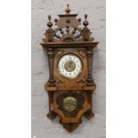 An early 20th century mahogany cased 8 day drop dial wall clock with enamel chapter ring with carved