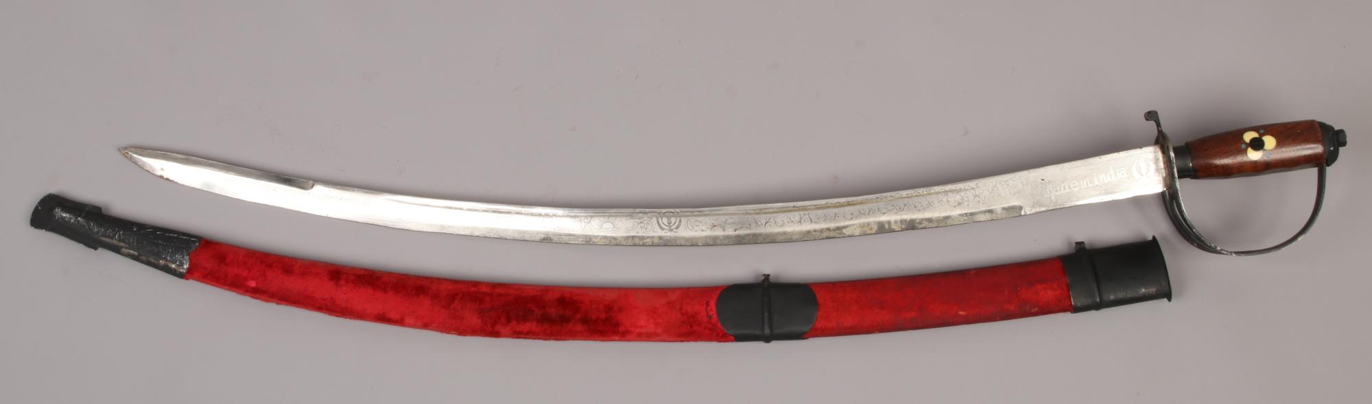 An Indian dress sword with inlaid hardwood grip, etched blade and velvet mounted scabbard.