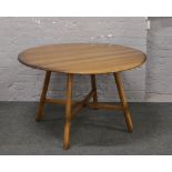 An Ercol Golden Dawn drop leaf circular dining table, raised on reeded square supports.