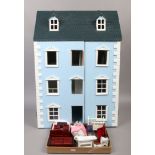 A three storey dolls house with dorma roof and a box of dolls house furniture.