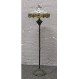 A Tiffany style standard lamp with ornate leaded coloured glass shade, raised on a reeded column