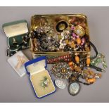 A tin of costume jewellery to include brooches, necklaces, wristwatch etc.