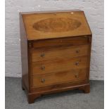 A mahogany and walnut bureau over four drawer base with partitioned interior and keys.