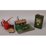A vintage stationary steam engine along with three oil cans to include Castrol and Esso cans.