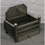 A polished metal fire basket with canted back.