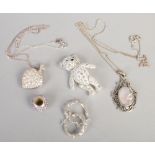 A small collection of silver jewellery including jointed teddy bear brooch and a heart shaped locket