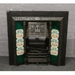 A Victorian style cast iron fire surround with Majolica style tiles.