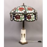 A Tiffany style table lamp with coloured leaded glass shade, raised on a brass and alabaster base.