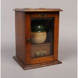 A carved oak smokers cabinet with bevel edge glass, lidded tobacco jar, pipes and accessories, along