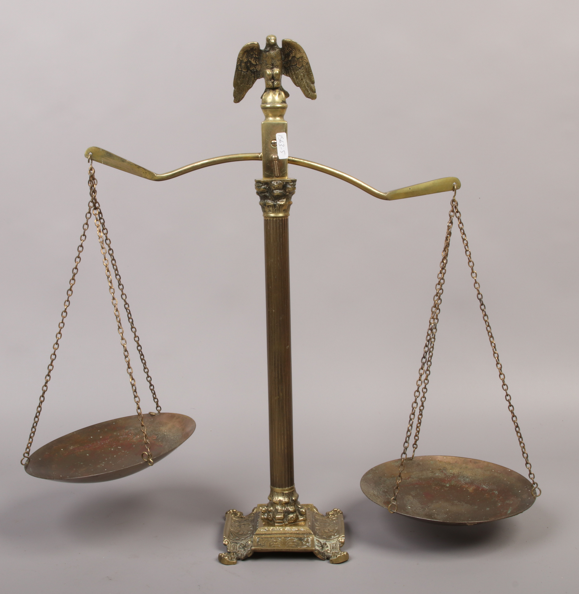 A set of brass scales with eagle finial and raised on a Corinthian column.