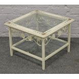 A white painted two tier glass top table decorated with roses.