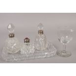Three silver mounted cut glass scent bottles, along with a Victorian drinking glass.