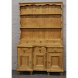 A carved pine breakfront kitchen dresser fitted with three spice drawers and raised on turned bun