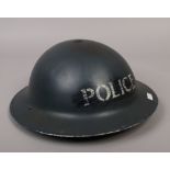 A vintage steel helmet, stencilled for Police.