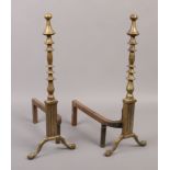 A pair of brass and cast iron fire dogs of knopped form and raised on ball and claw feet.