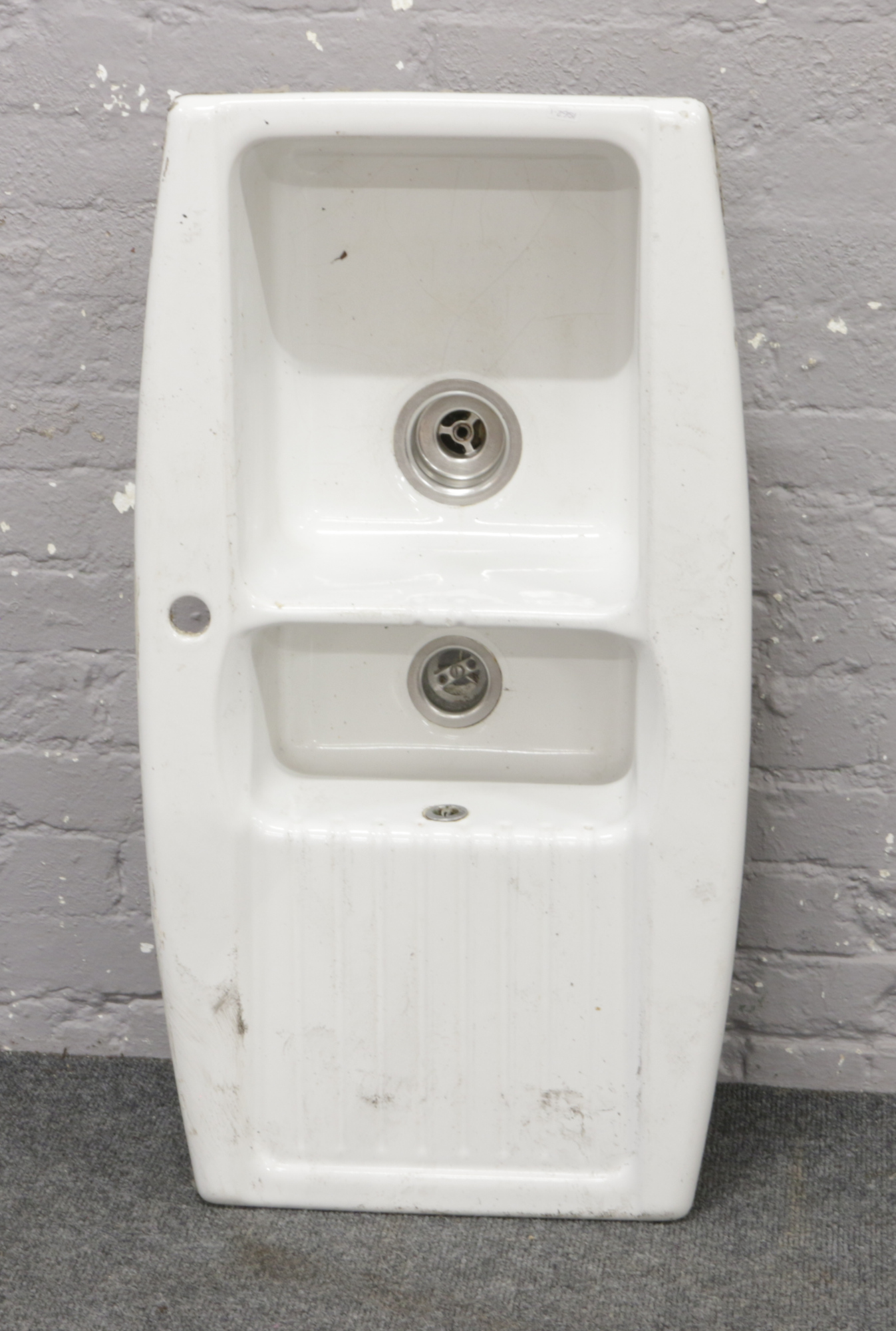 A ceramic kitchen sink with rinsing bowl.