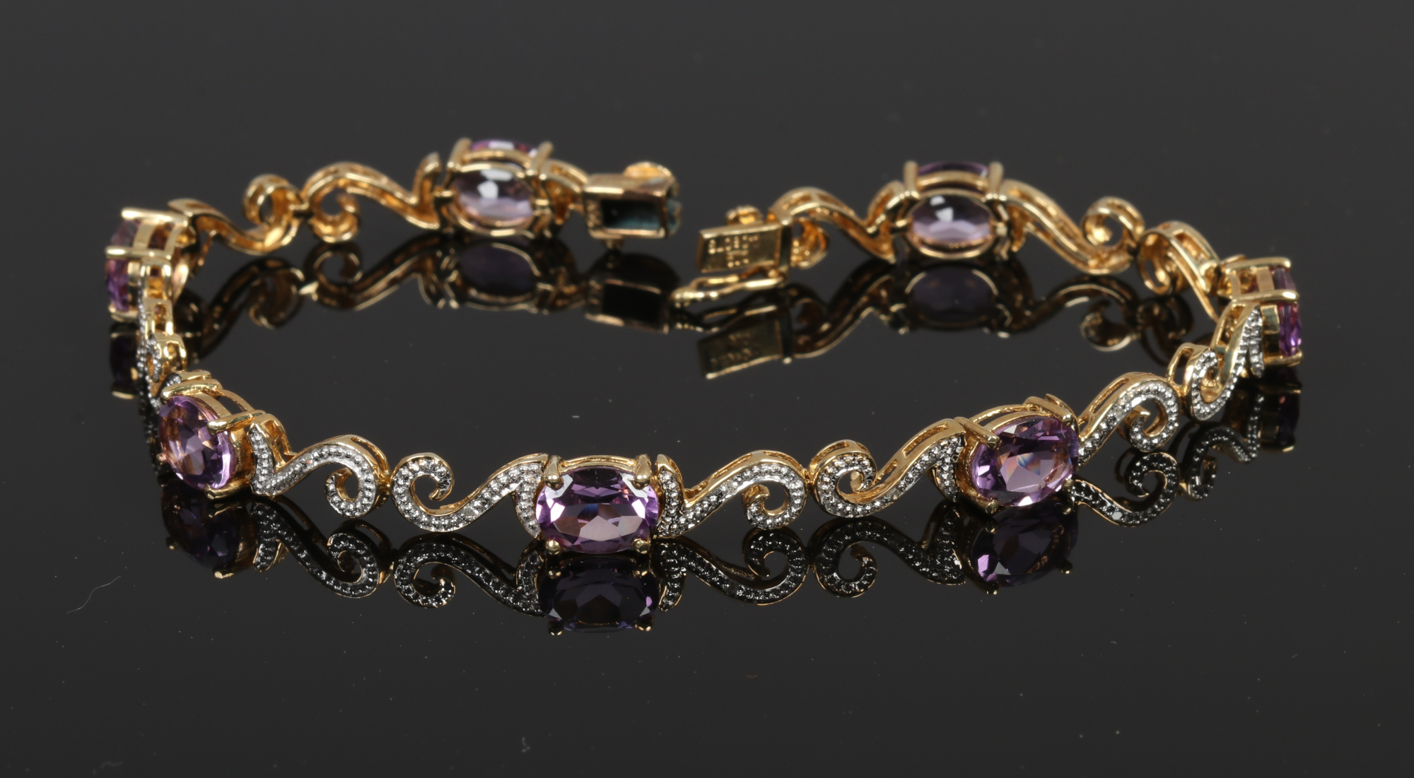 A 9ct gold amethyst and diamond bracelet with scroll shaped link.