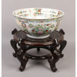 A decorative Cantonese punch bowl on Chinese wooden stand.