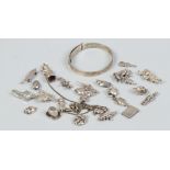 A quantity of silver and white metal charms along with a silver christening bangle.
