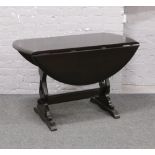 An ebonised drop leaf dining table with refectory base.