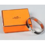 A boxed Hermes Paris Clic H bracelet with black enamel decoration.