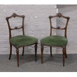 A pair of Victorian mahogany salon chairs raised on turned and reeded supports.