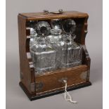 A locking oak tantalus with silver plated mounts with mirrored back panel and two cut lead crystal
