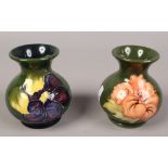 Two Moorcroft green ground baluster vases, one in the Hibiscus design the other in The Clematis