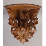 An early 20th century Black Forest corner bracket shelf, carved with the head of a Deer and acanthus