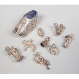 A collection of silver charms and a continental silver Dutch dog pin cushion.