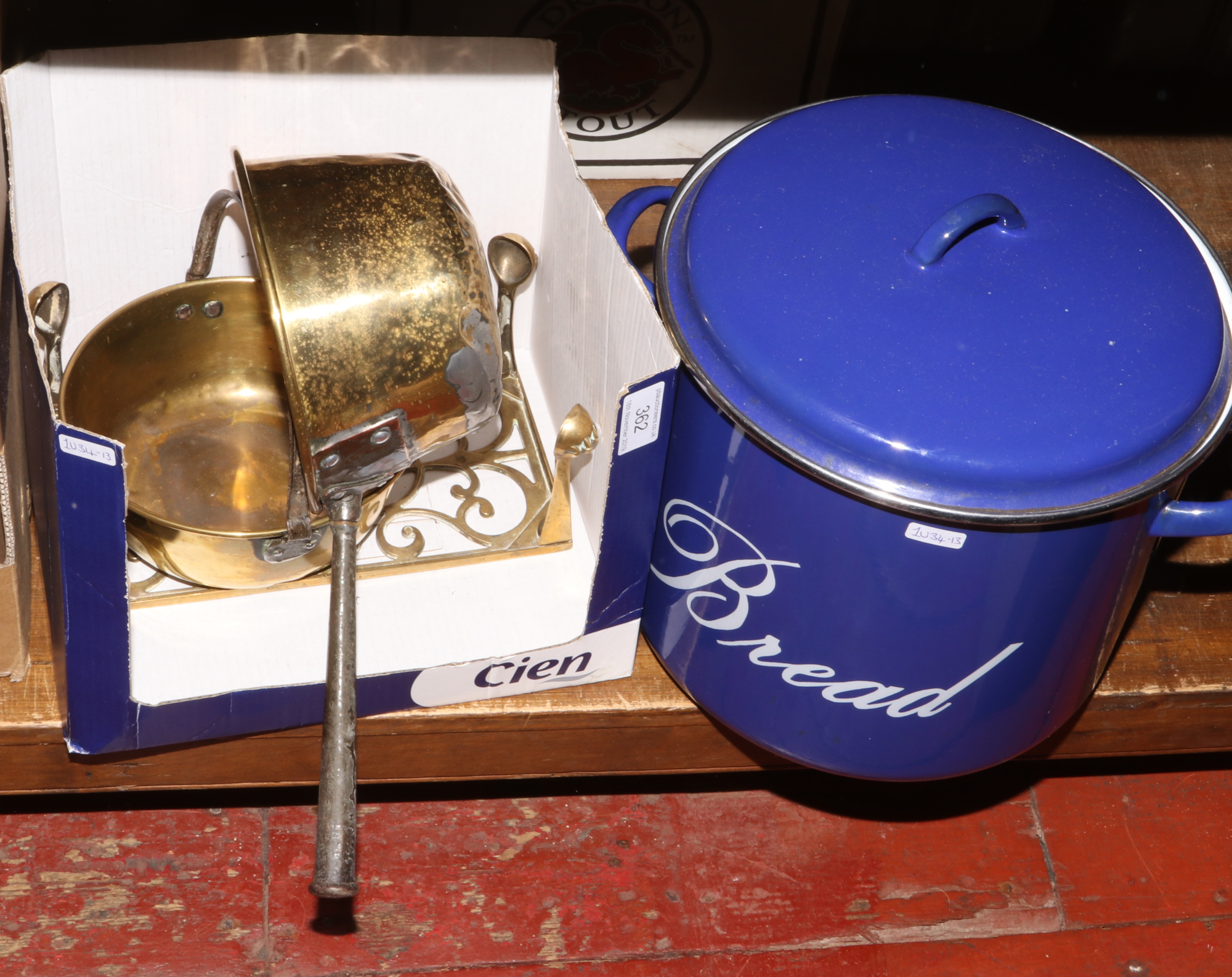 A twin handle enamel bread bin along with brass trivet and pans.