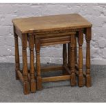 A nest of three oak occasional tables raised on turned and square cut legs.